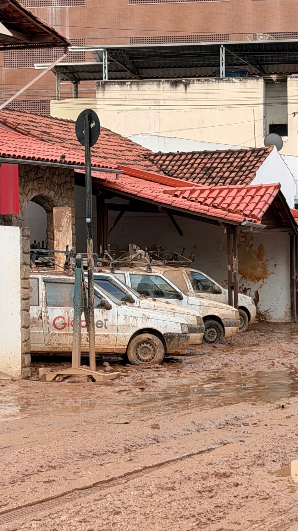 Carros e ruas cobertos de lama após a enchente em Ubá