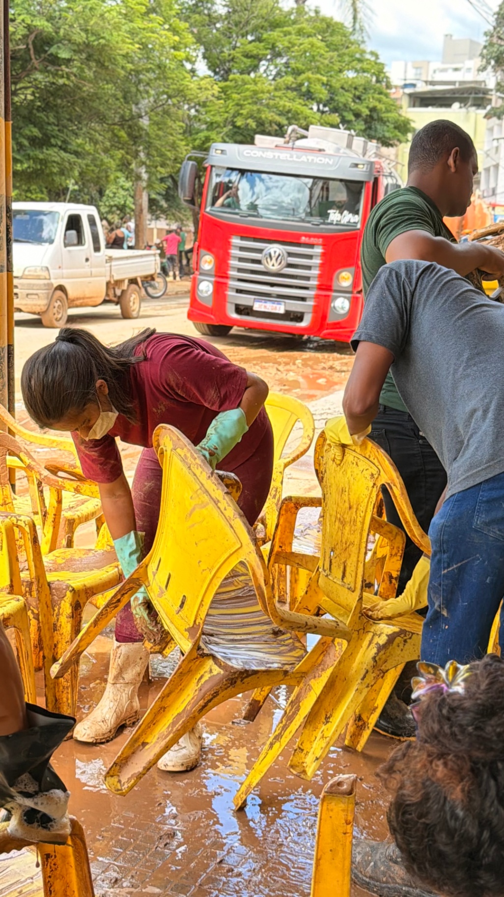 Voluntários lavando cadeiras cobertas de lama na rua